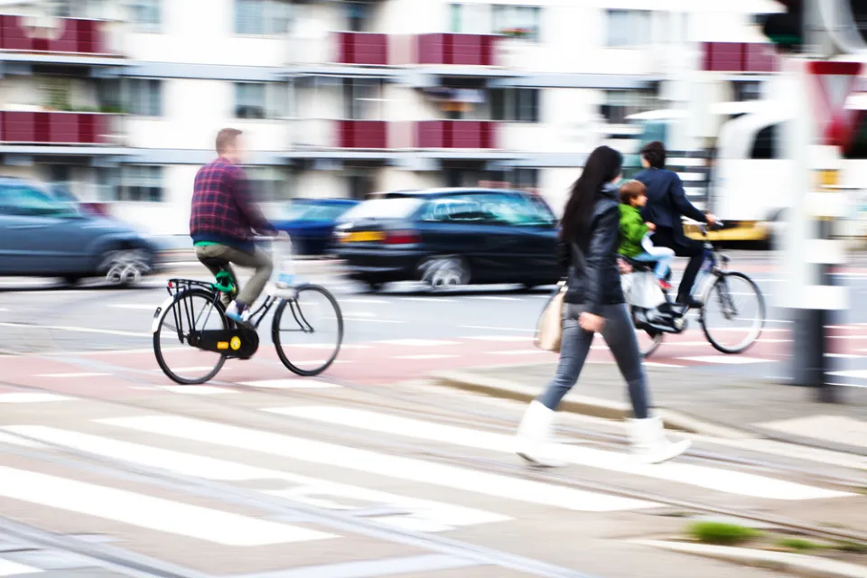 Pedestrians and cyclists in busy city crosswalk with blurred motion